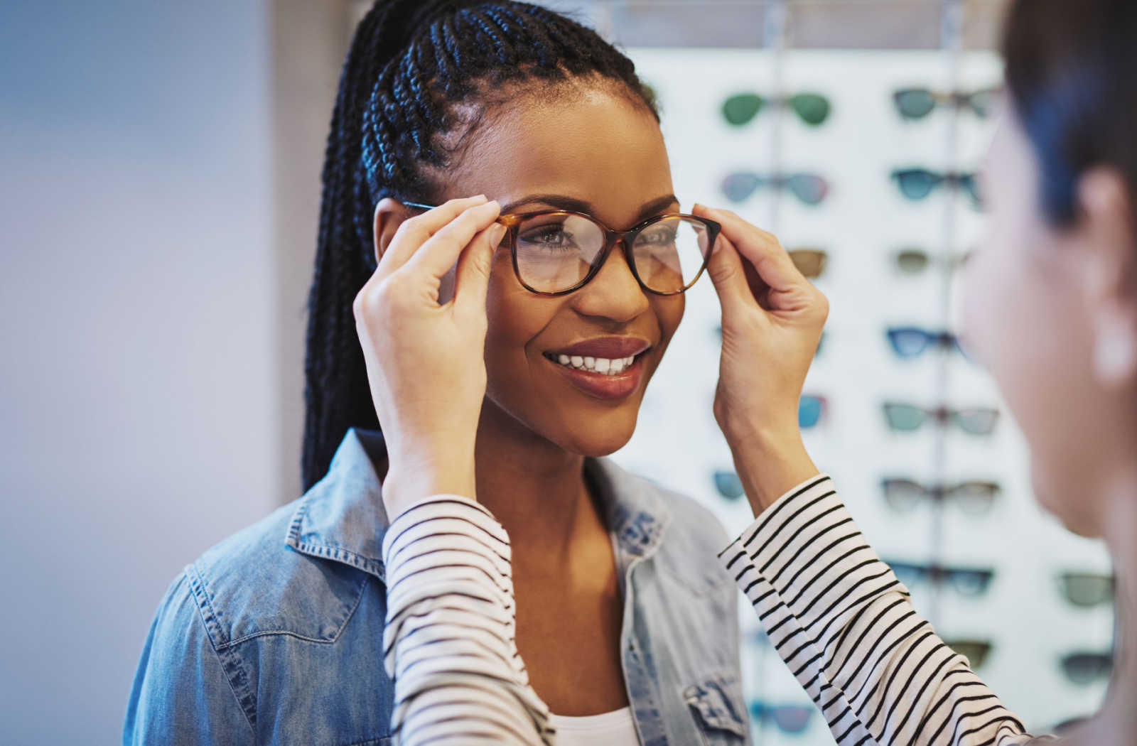 An optician helping a patient find the right pair of glasses that fit and sit correctly on the nose