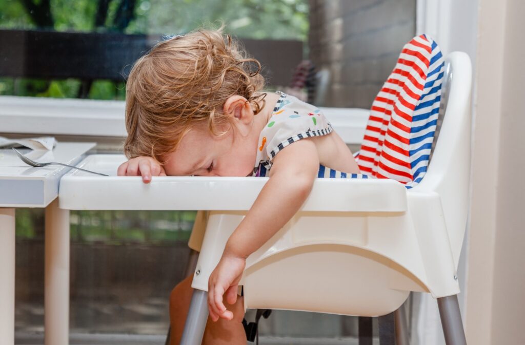 A tired baby falling asleep in their high chair.