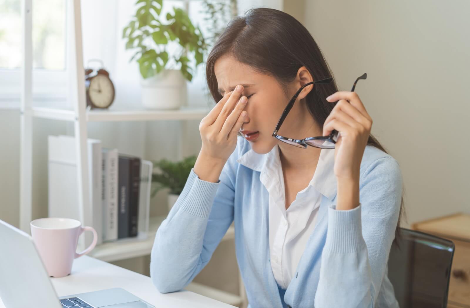 Woman rubbing her eyes, showing discomfort from dry eye symptoms.