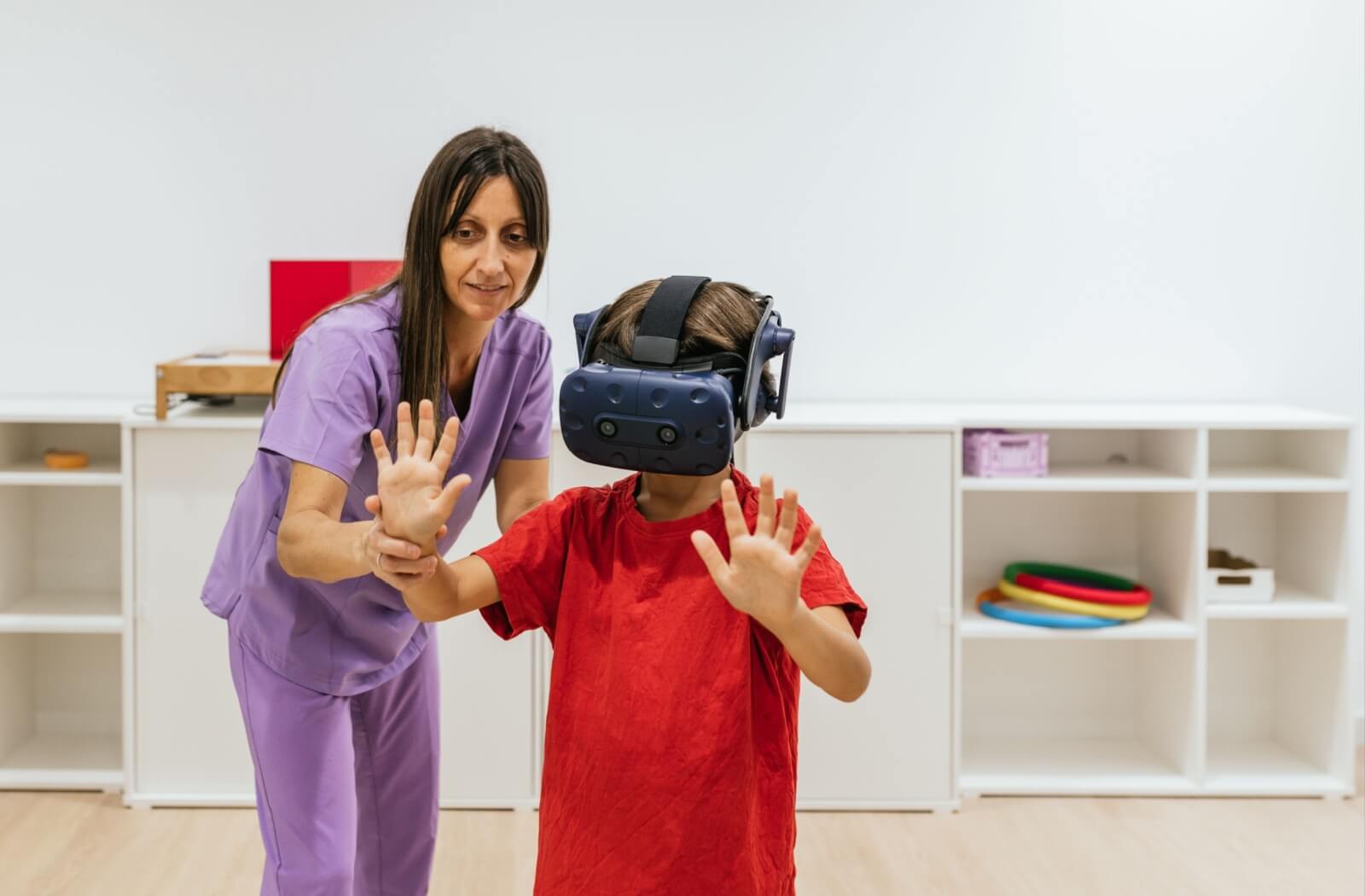 An eye doctor guides their child patient through a VR technology vision therapy exercise.